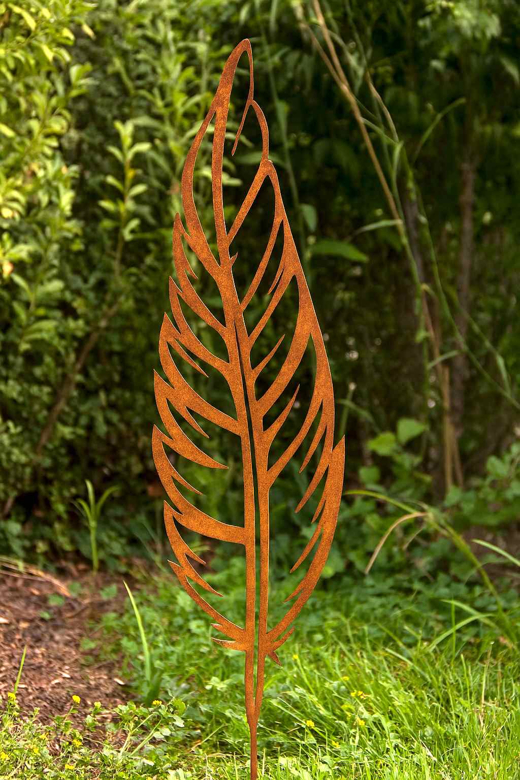 Edelrost Feder Gartenstecker aus Stahl in natürlicher Rostpatina zwischen Grünpflanzen
