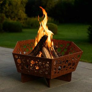 Sechseckige Feuerschale Bubbles aus Edelrost Stahl mit runden Ausschnitten und brennendem Feuer im Garten