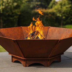 Große achteckige Feuerschale aus Edelrost Stahl mit brennendem Feuer im Garten – massive handgefertigte Feuerstelle aus 5 mm Stahl